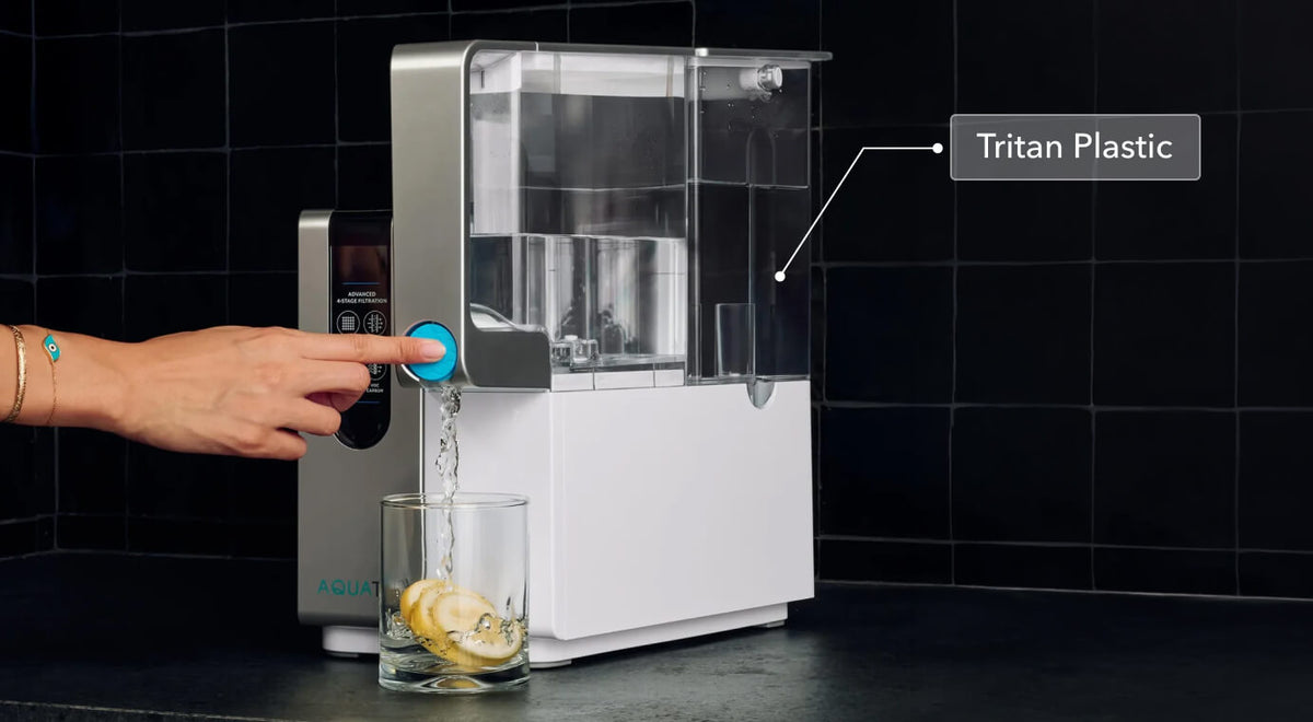 Water dispenser with a hand pressing a button, pouring water into a glass with lemon slices, labeled "Tritan Plastic.