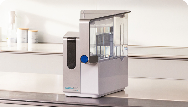 AQUATru water purification system on a countertop with a clean, modern design and a blue control knob.