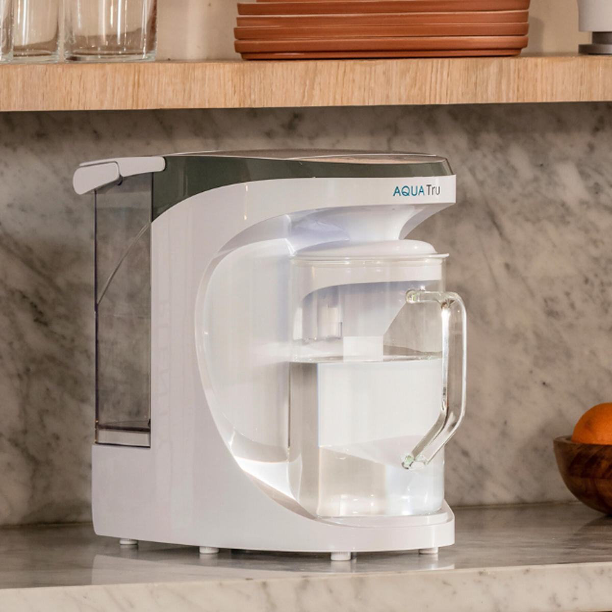 AquaTru Carafe with free pre-carbon filter, sleek white design on a marble countertop.