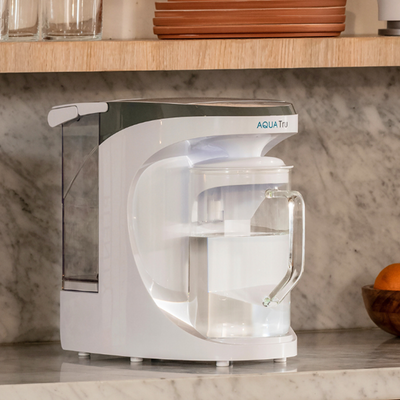 AquaTru Carafe with free pre-carbon filter, sleek white design on a marble countertop.