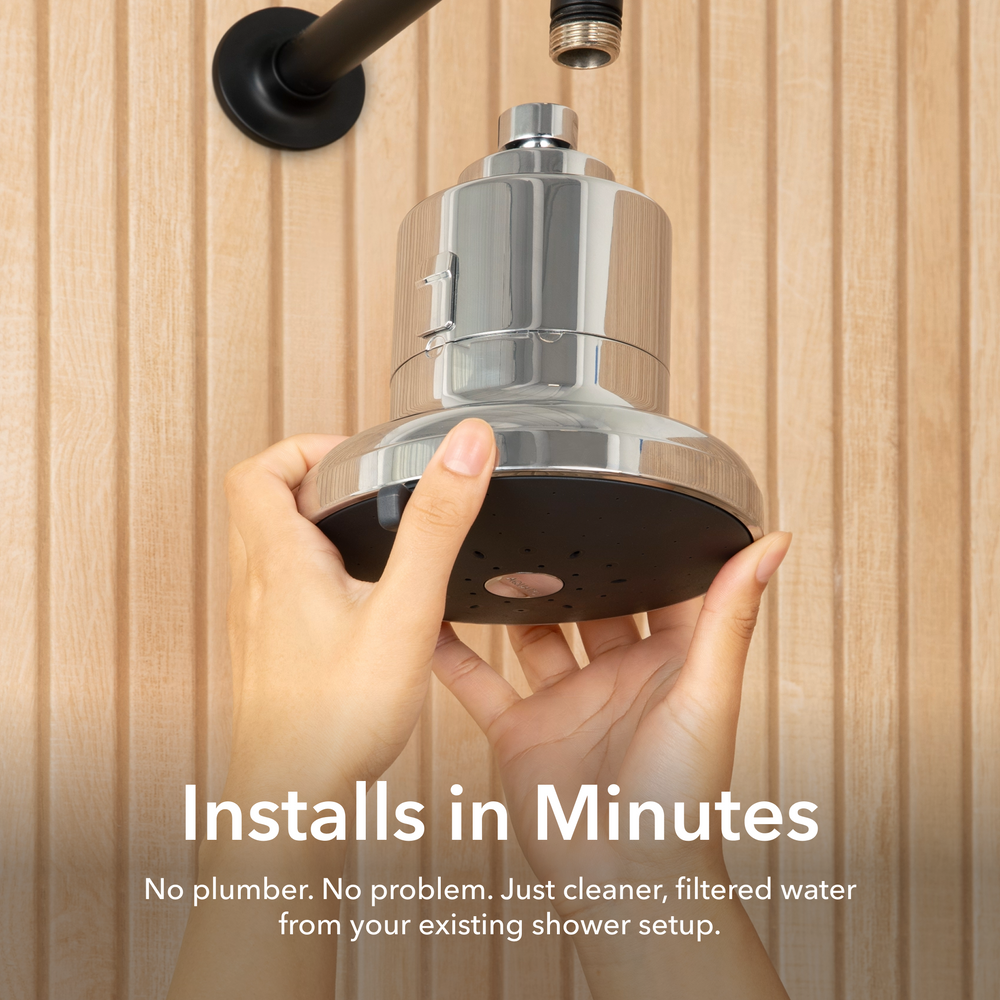 Installs in Minutes. No plumber. No problem. Just cleaner, filtered water from your existing shower setup. Image shows a person's hands holding up a chrome filtered shower head to attach it to an existing black shower arm.
