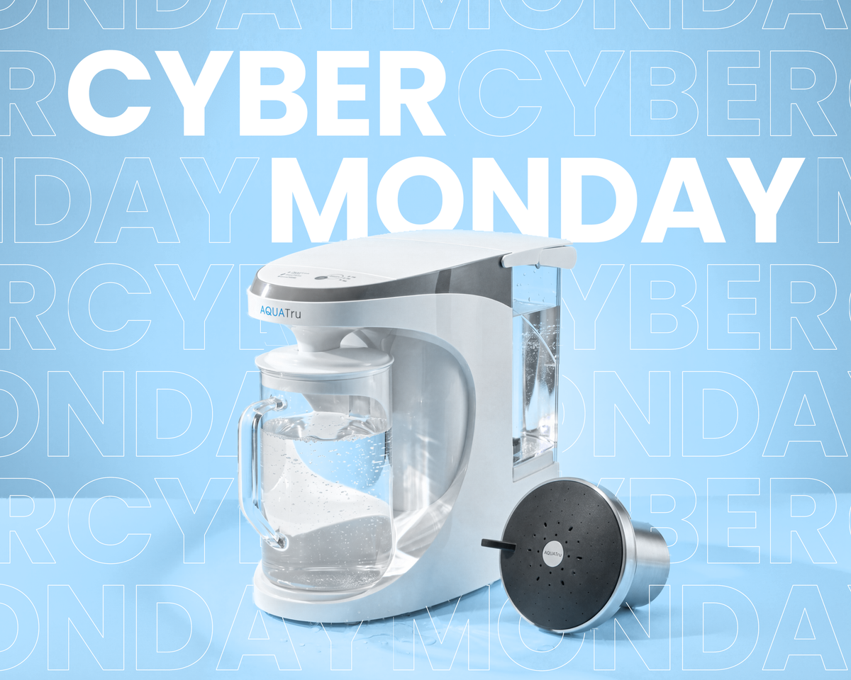 An AquaTru Carafe and AquaTru Shower on a light blue background with the words "Cyber Monday" above the Carafe and embedded in the blue background.