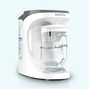 AQUAtru water filtration system with a clear carafe, water flowing into the container, and a sleek white design.