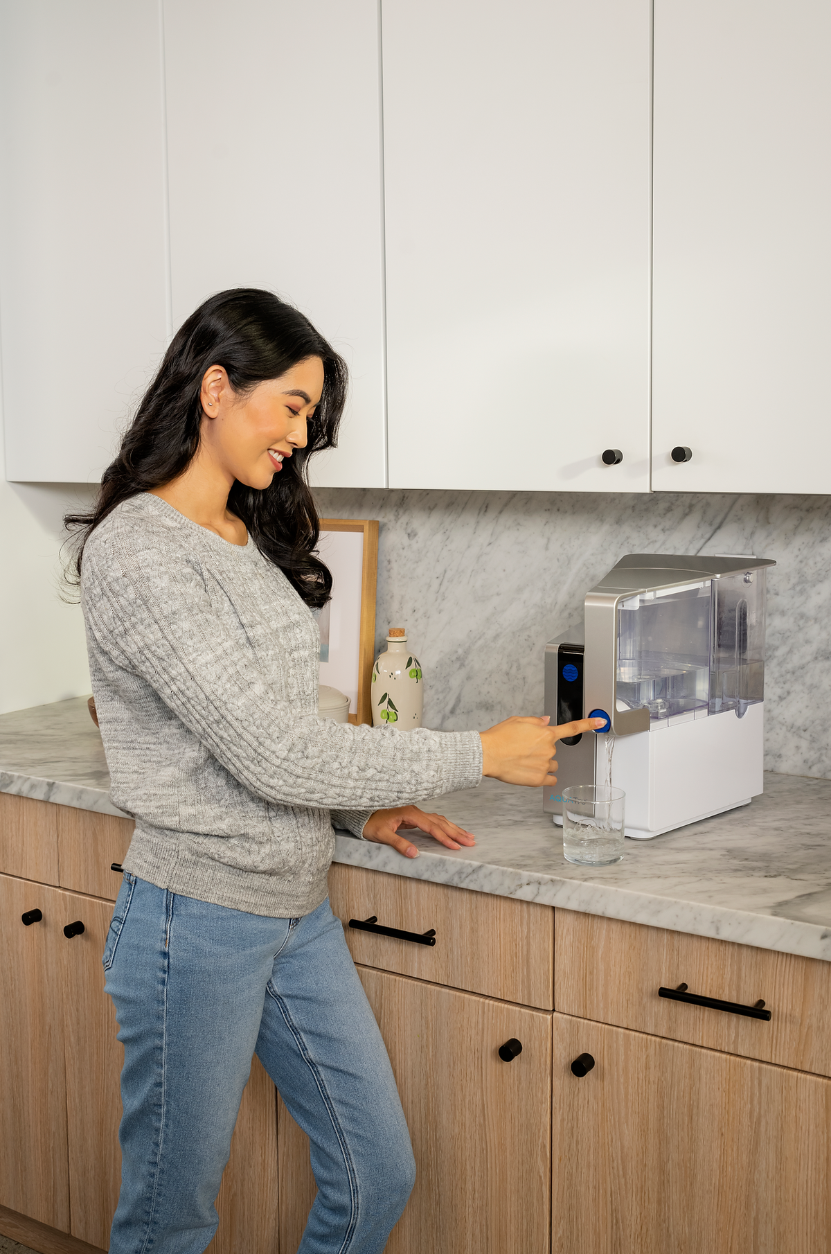 Medium AQT Classic water dispenser on a kitchen counter, with a woman filling a glass and smiling.