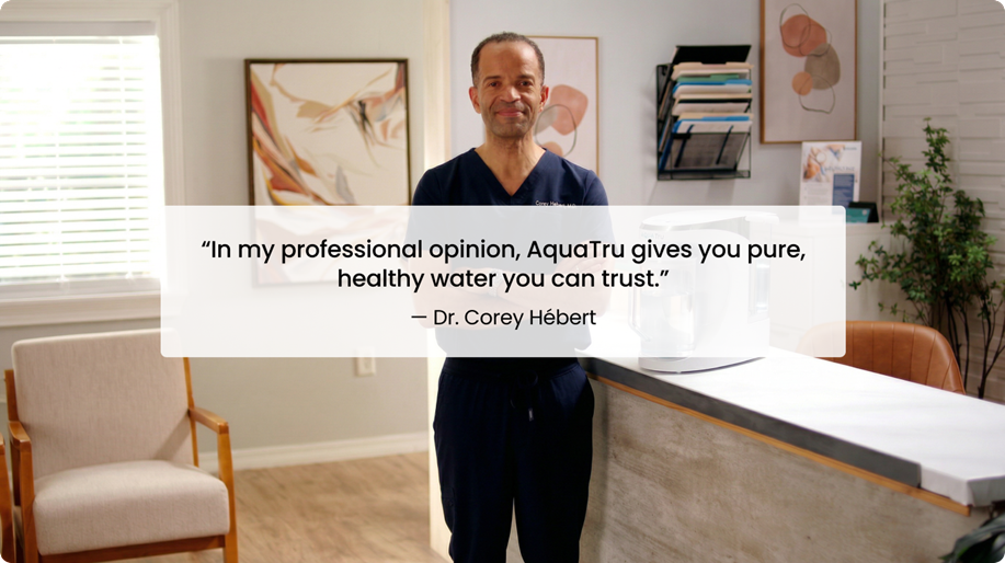 A man in scrubs stands beside a water filtration system, sharing a quote about AquaTru's water quality.