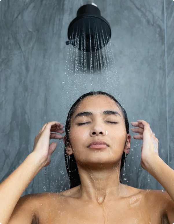 Person showering with a black AquaTru showerhead.