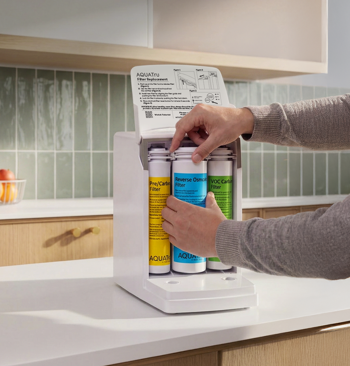 A person's hands are shown installing three replacement water filter canisters into a white countertop water dispenser. The dispenser is set on a white kitchen counter with a light green tiled backsplash in the background.