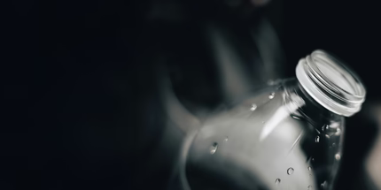 Close-up of a clear plastic bottle with a silver cap on a dark background