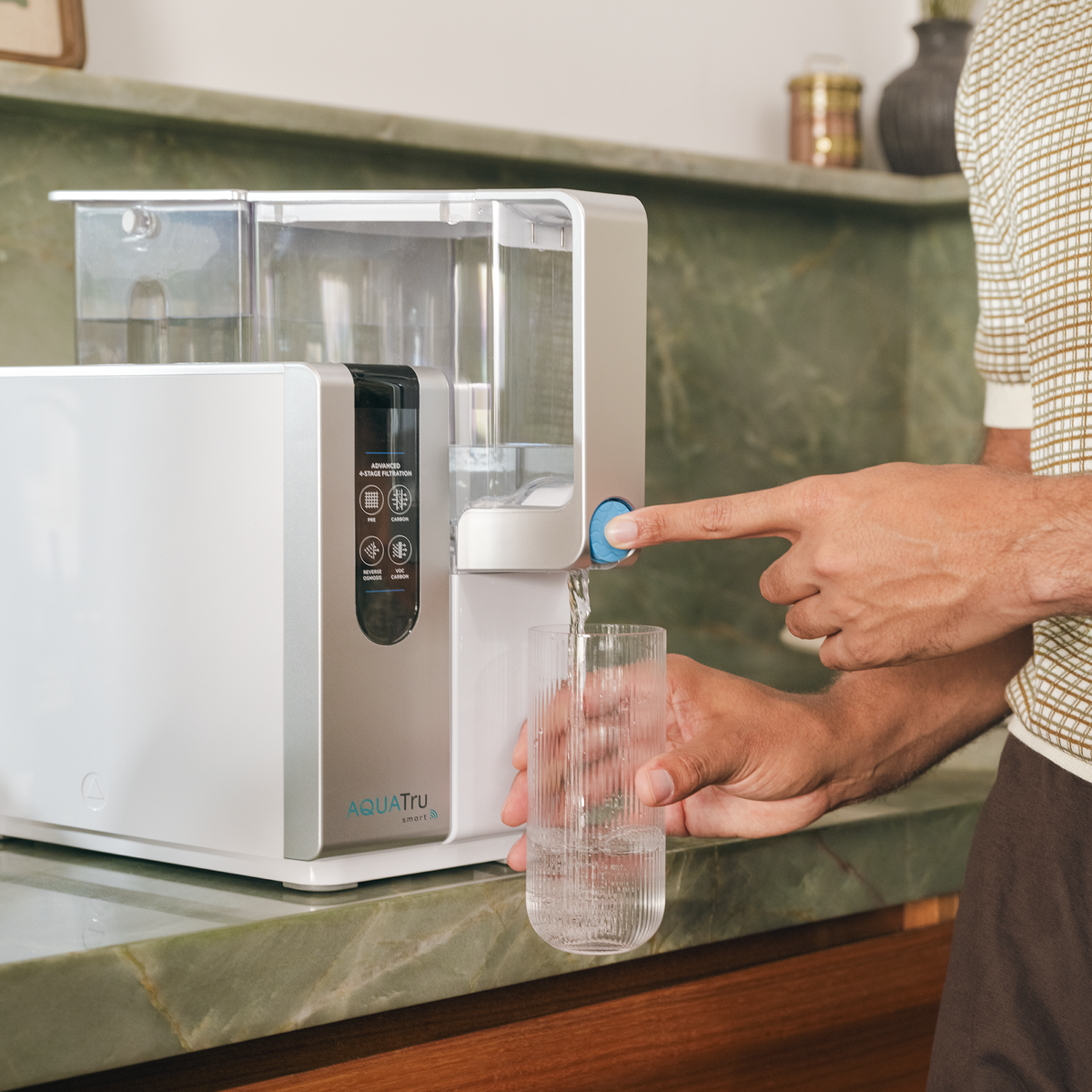 Closeup of a man's hands as he dispenses water into a glass from an AquaTru Classic water purifier
